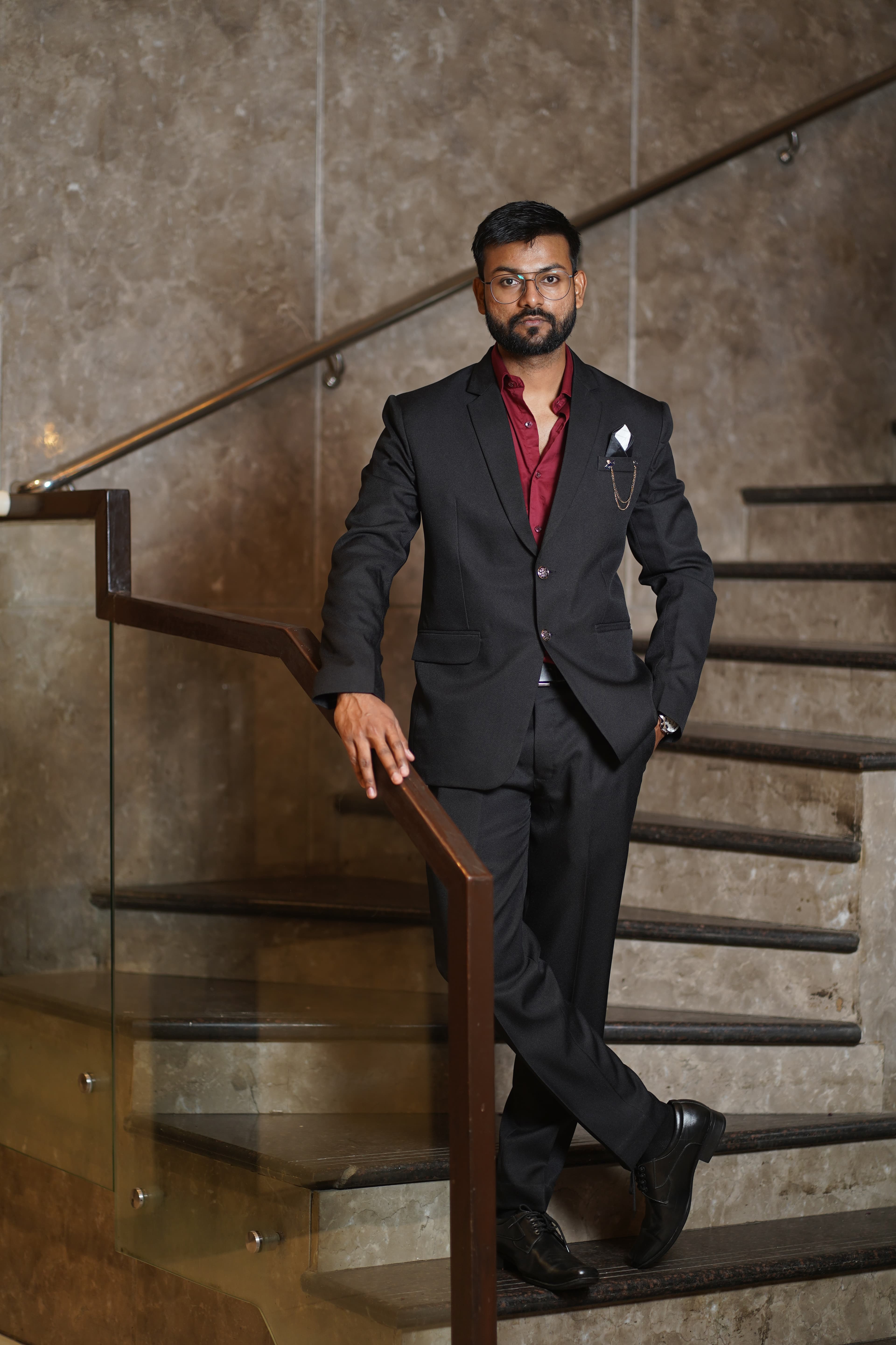 Professional portrait in black blazer and maroon shirt on marble stairs