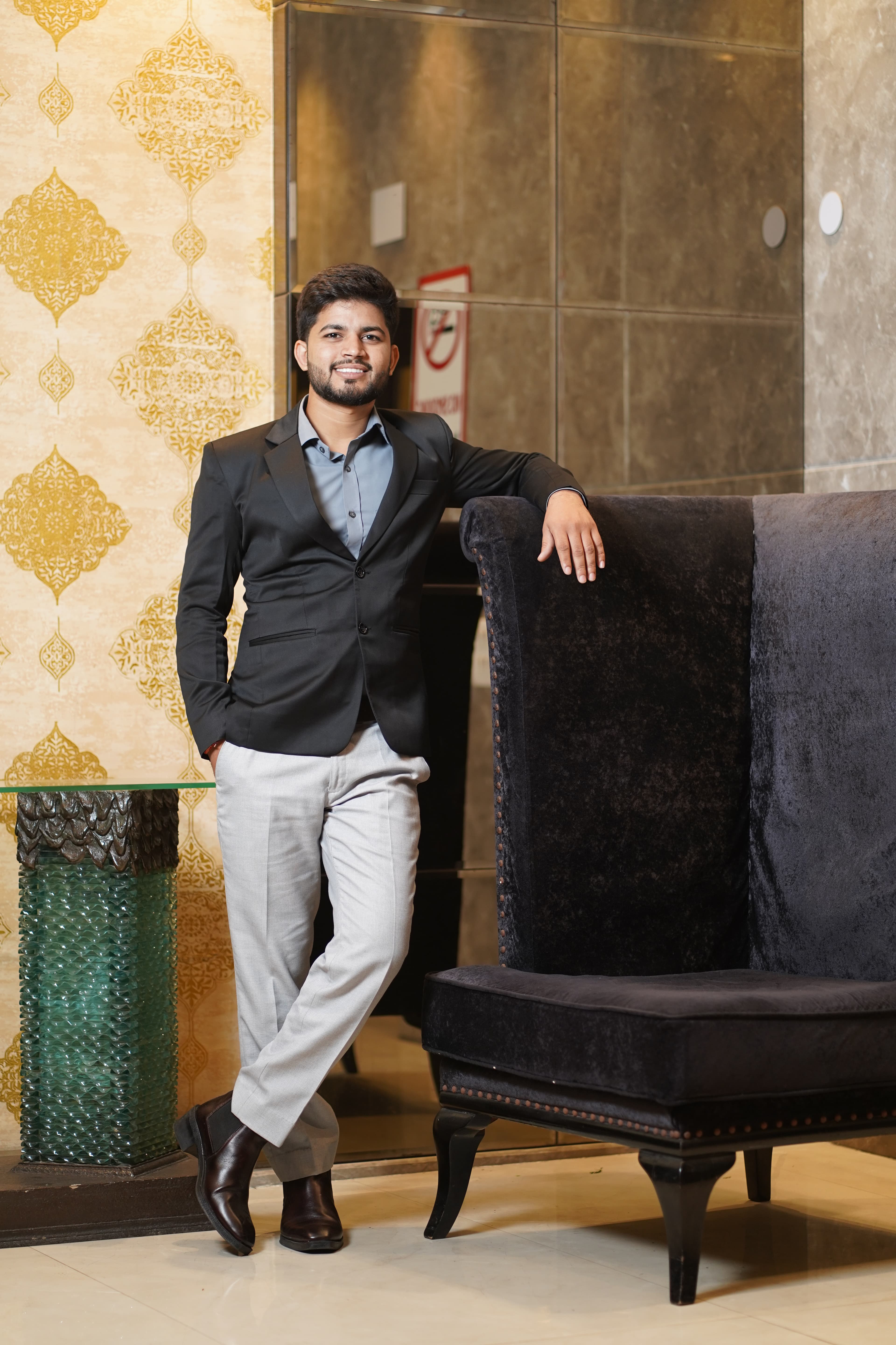 Full-length portrait in blazer and light trousers in an upscale lounge