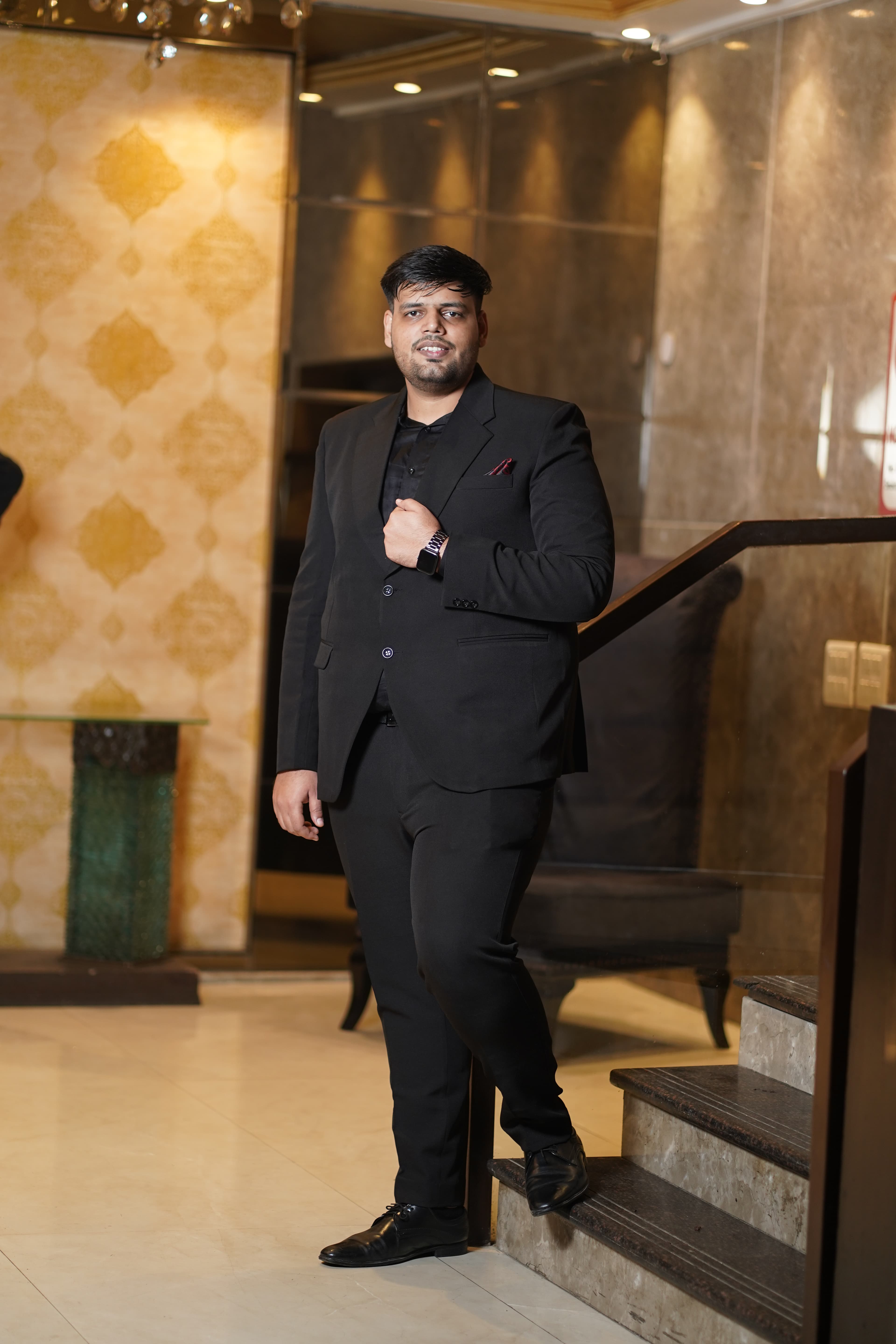 Full-length portrait in black suit on a marble staircase
