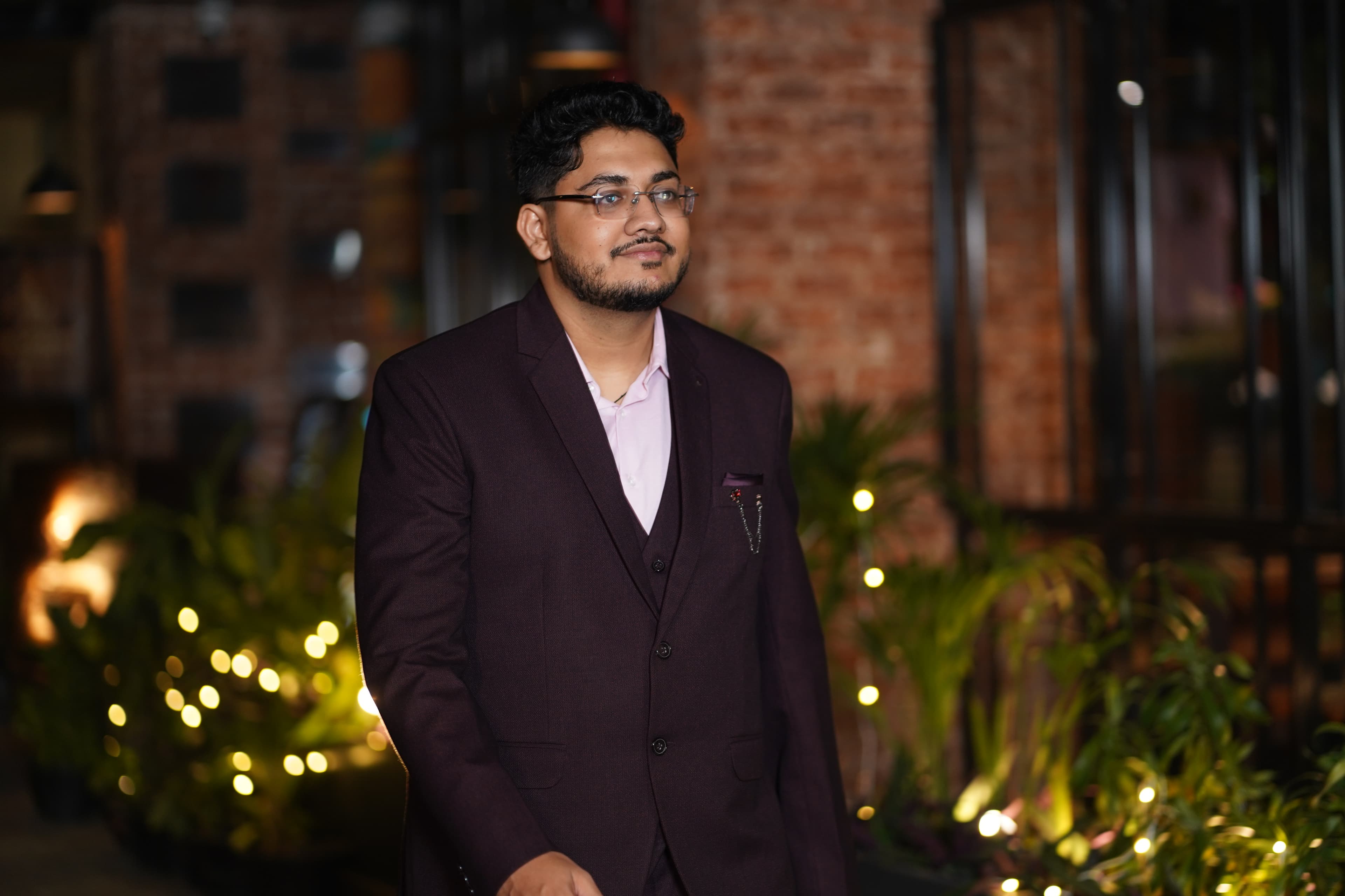 Portrait in burgundy three-piece suit with brick wall and ambient lighting